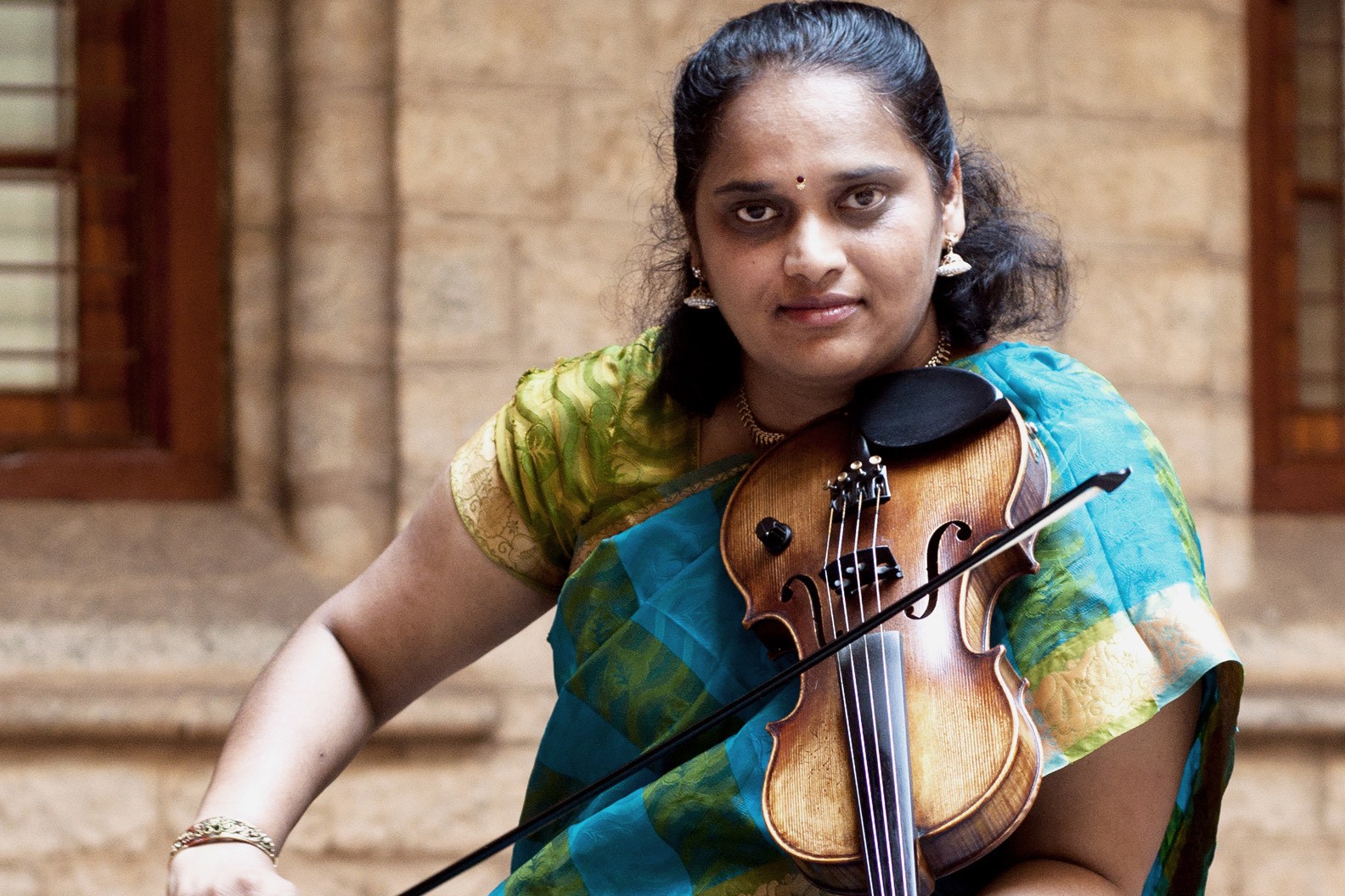 Jyotsna Srikanth, holding her violin across her body, bowing it.